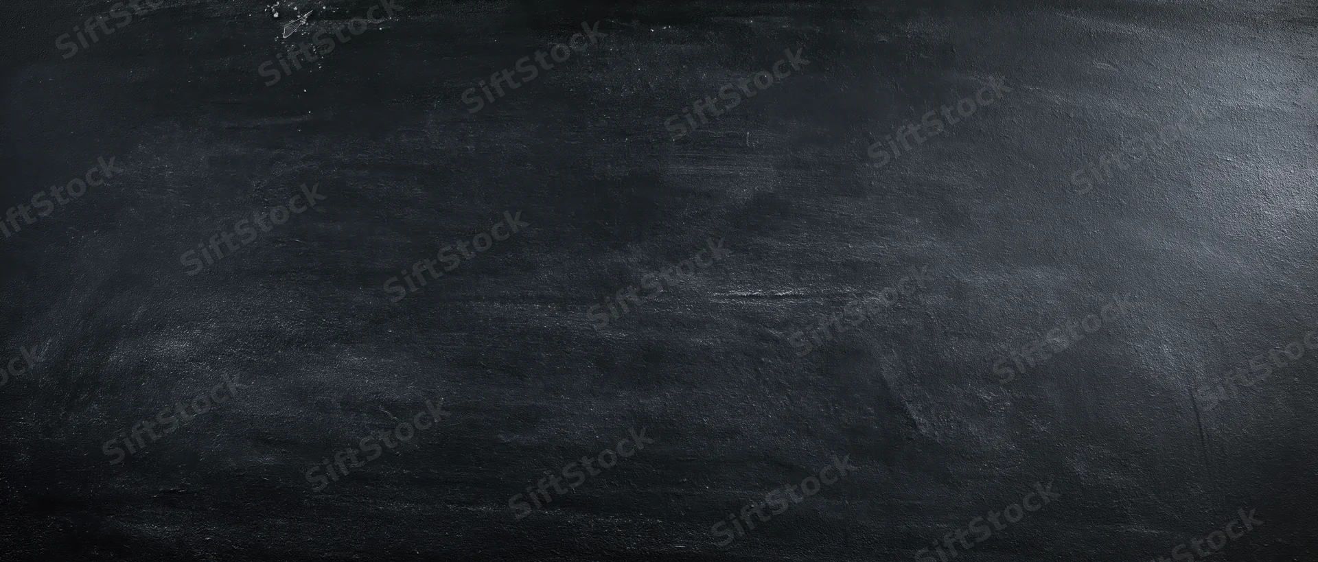 Dark textured blackboard surface with chalk residue and smudges, showing signs of use and wear