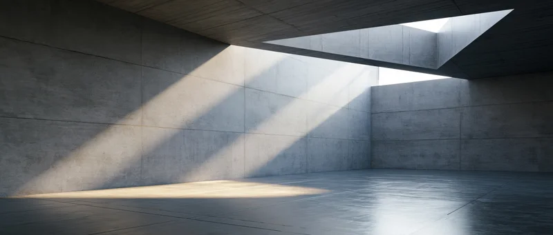 Empty concrete room with angular skylight casting diagonal light and shadow across walls and floor