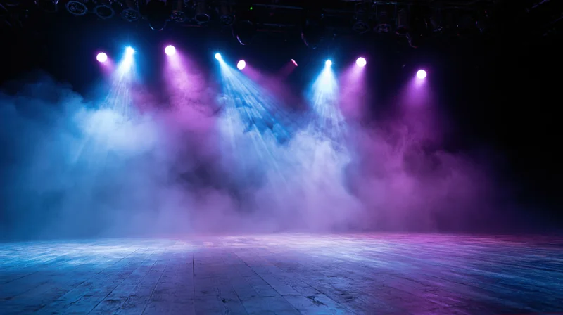 Empty stage lit by blue and purple spotlights with smoke filling the air