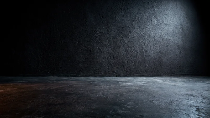 Dark textured concrete floor and wall in empty industrial studio space with spotlight and shadow