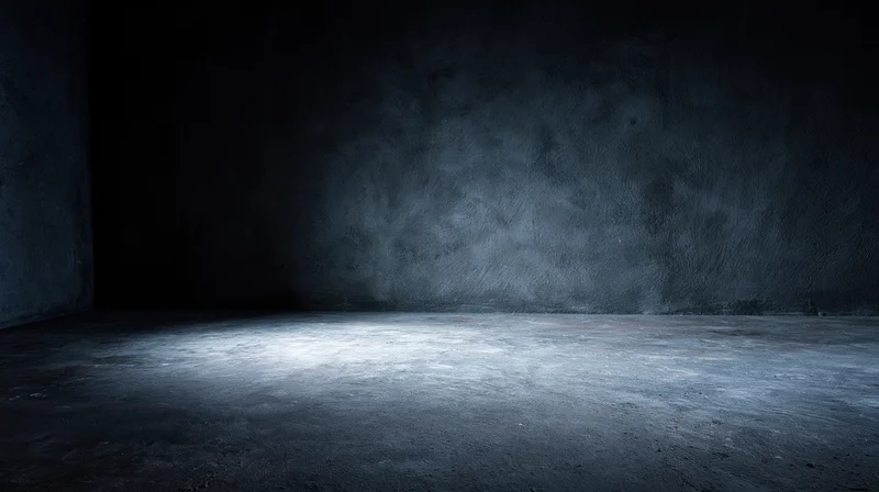 Empty concrete room illuminated by a spotlight in a dark interior