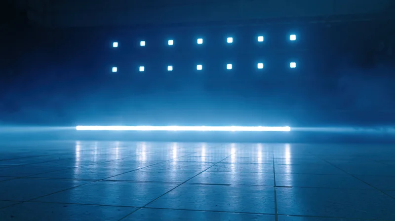 Blue neon lights arranged in grid and horizontal beam reflecting on tiled floor in smoky studio space