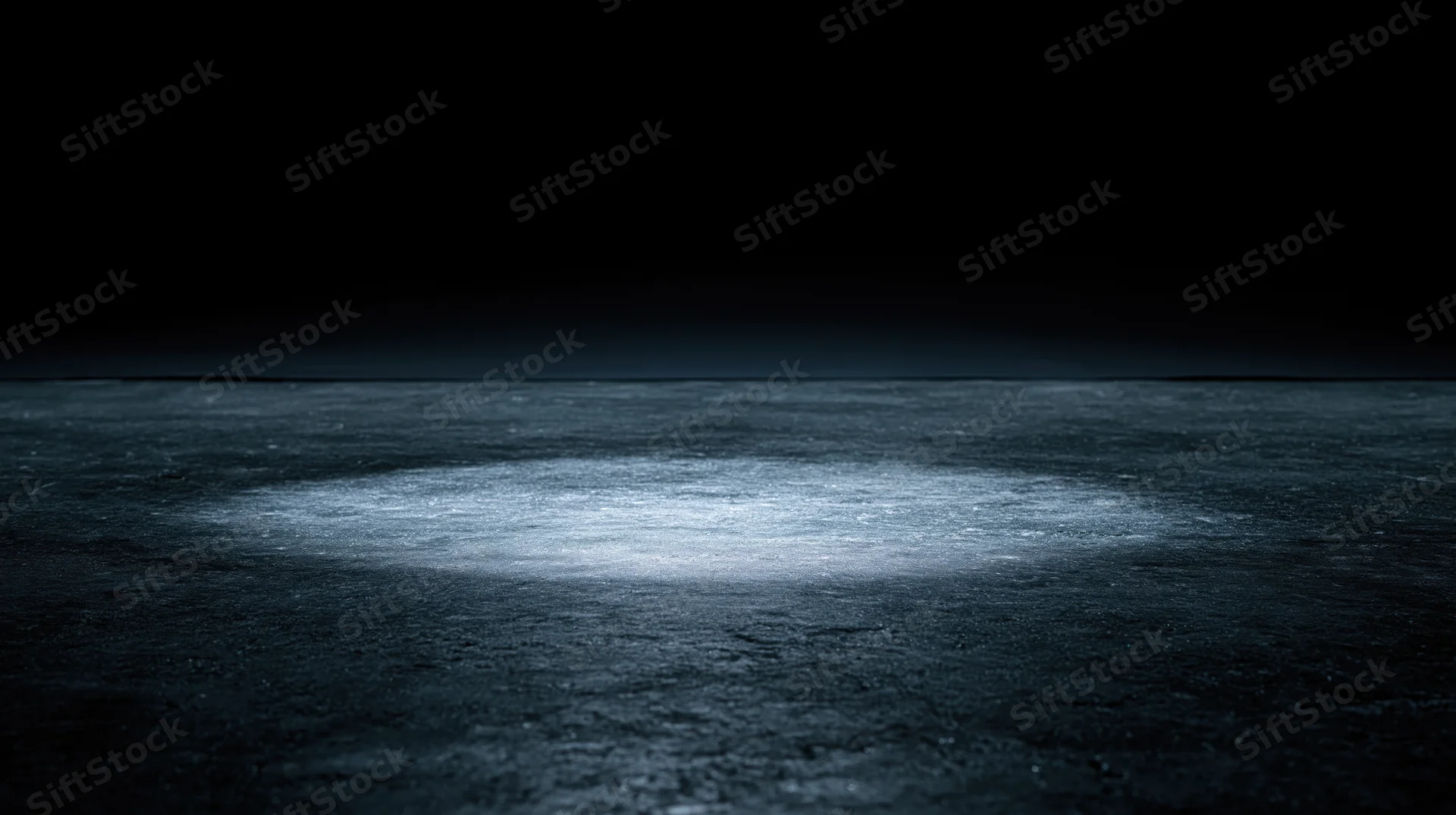 Spotlight illuminating a circular area on a dark textured floor at night