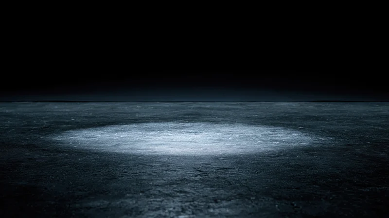 Spotlight illuminating a circular area on a dark textured floor at night