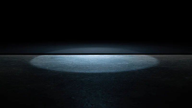 Spotlight beam on dark floor creating illuminated circular center stage area