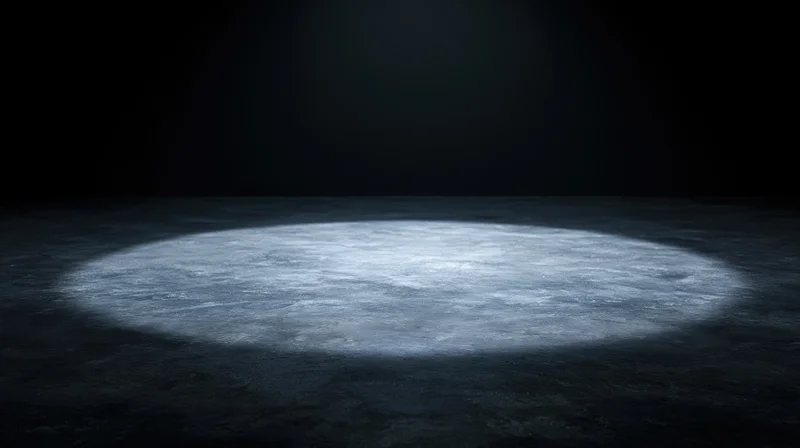 Circular spotlight on dark concrete floor in empty stage space