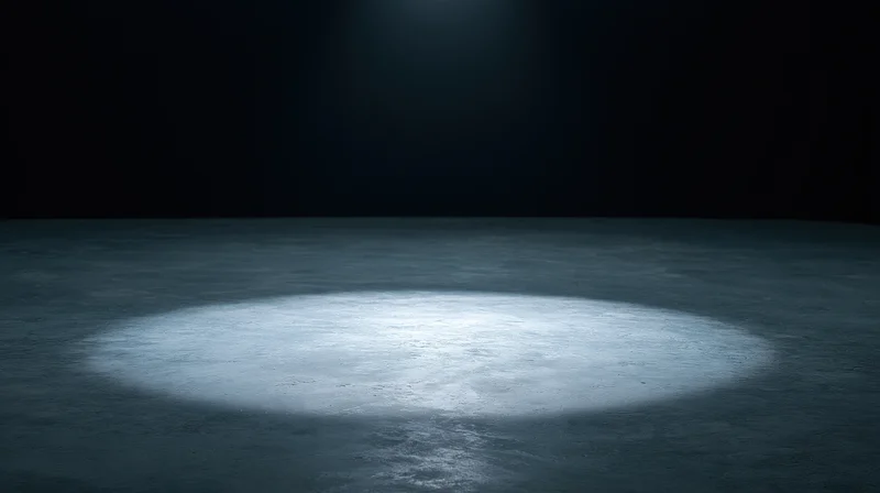 Spotlight beam on empty concrete floor in dark theater stage