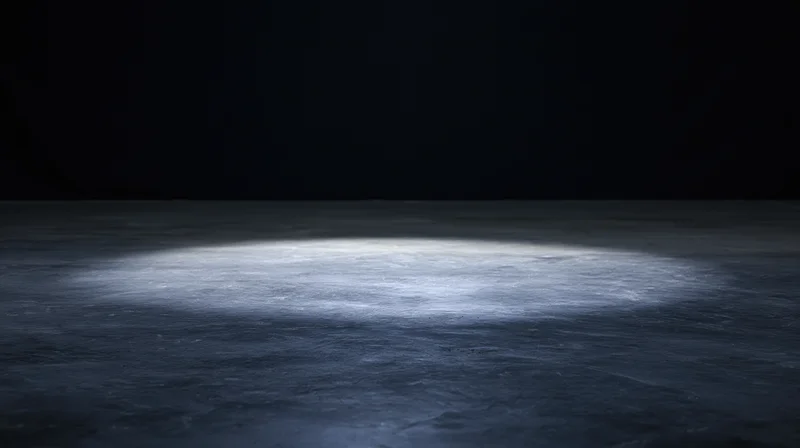 Spotlight on empty concrete floor in dark studio space