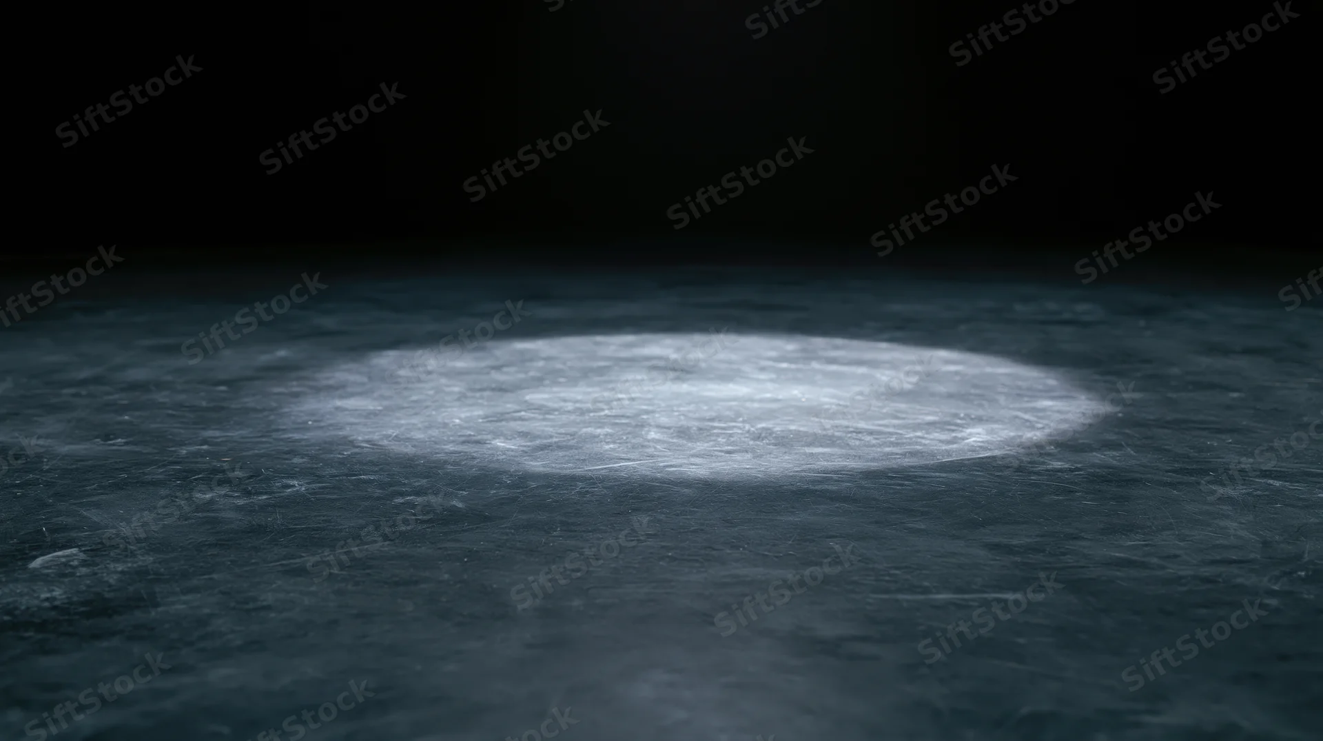 A circular spotlight illuminates a dark textured floor, casting a bright beam in the center of the frame