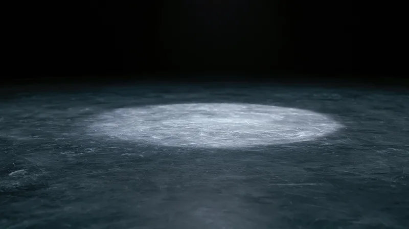 A circular spotlight illuminates a dark textured floor, casting a bright beam in the center of the frame