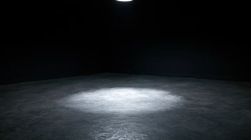 Spotlight beam on concrete floor in dark empty room