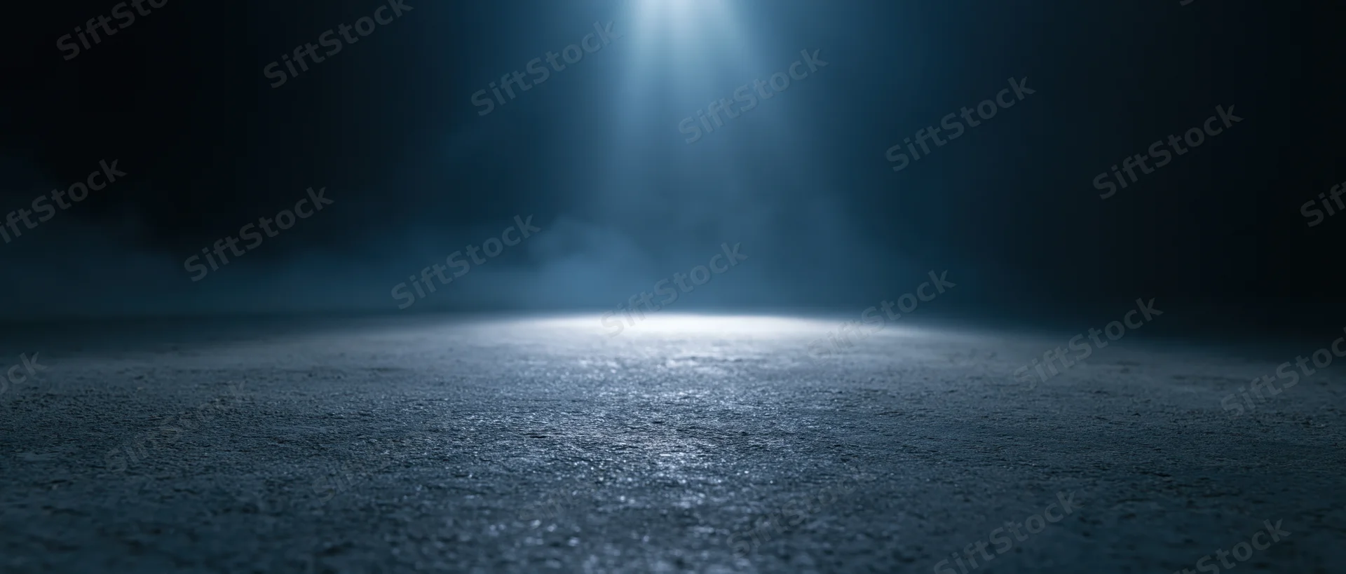 A spotlight beam illuminating a dark concrete floor with haze and reflection