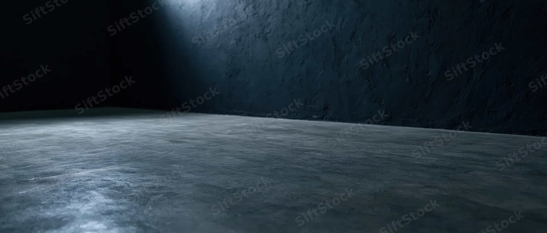 Dark empty room with concrete floor and textured wall lit by a single light source in the corner