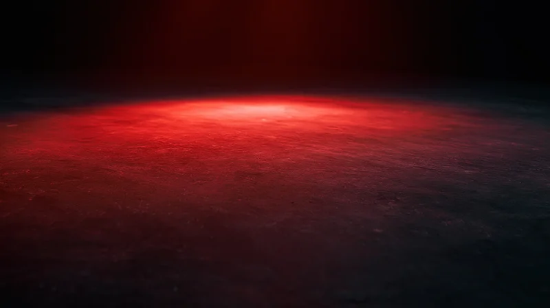 Red glowing light on dark textured surface with ambient illumination and shadowed edges