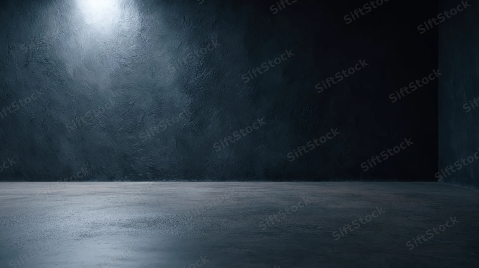 Empty concrete room with spotlight on textured wall and floor, interior studio space