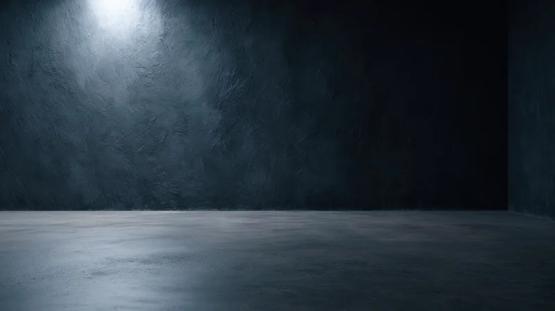 Empty concrete room with spotlight on textured wall and floor, interior studio space