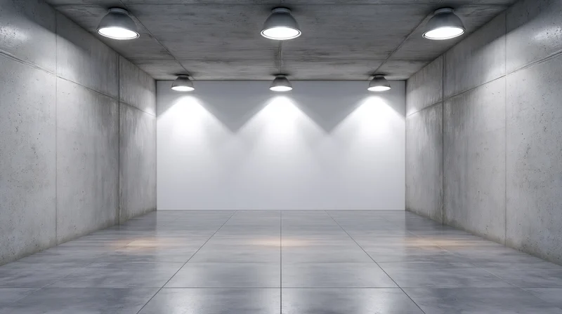 Empty gallery space with white wall and spotlights on concrete ceiling and floor