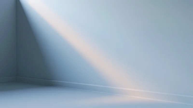 A diagonal beam of light illuminating a corner of an empty room with white walls and floor
