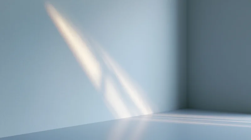 Diagonal light beam casting soft shadow on blue wall and floor in empty room corner