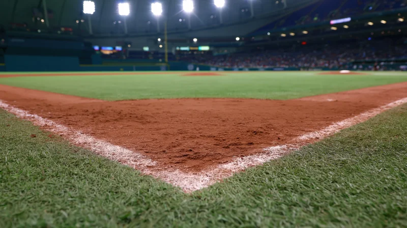 Close-up of baseball field corner with dirt and white chalk line at stadium during evening game