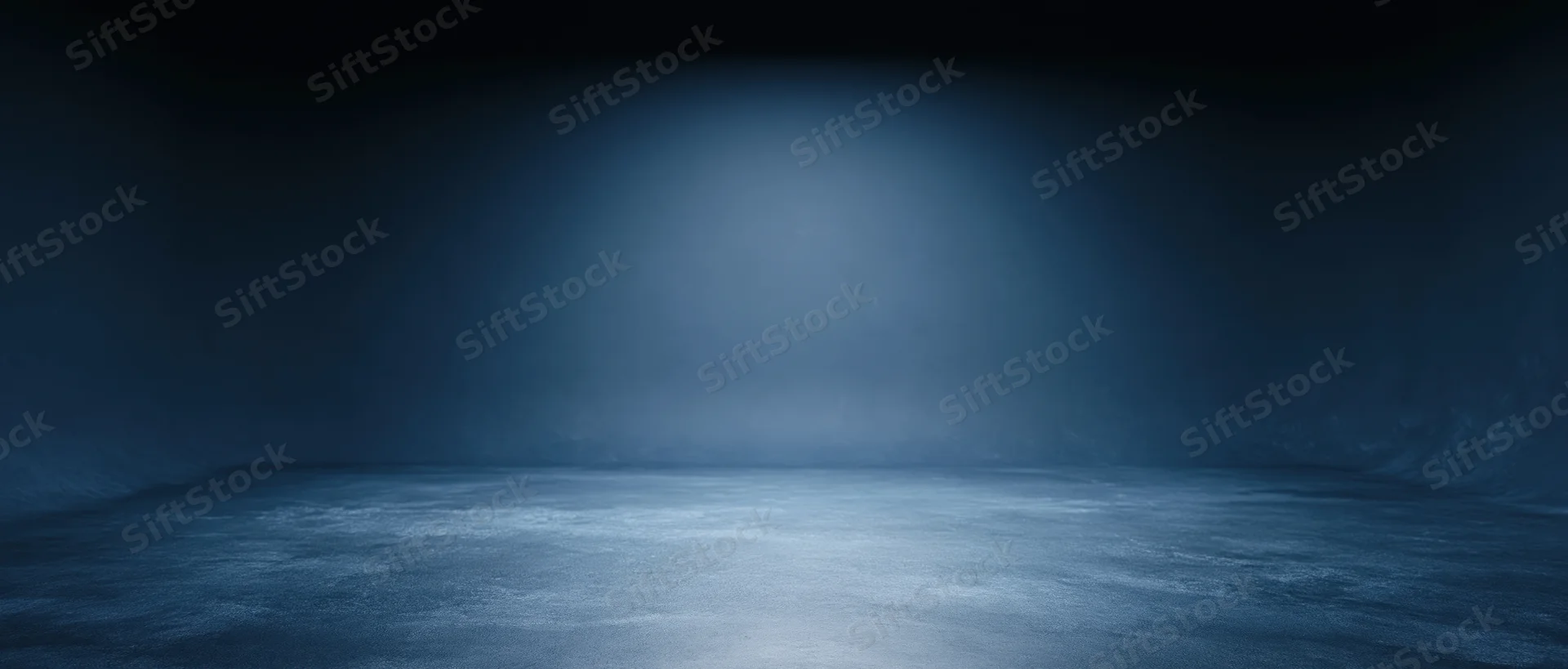 Empty room illuminated by a spotlight on a dark blue floor with atmospheric haze and copyspace
