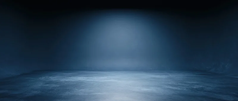 Empty room illuminated by a spotlight on a dark blue floor with atmospheric haze and copyspace