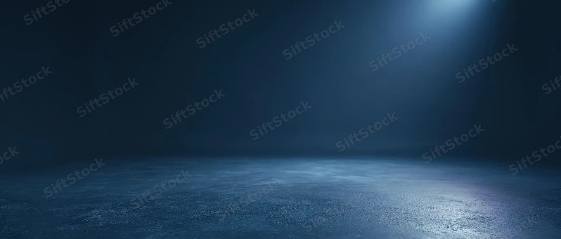 Spotlight illuminating an empty concrete floor in a dark studio space