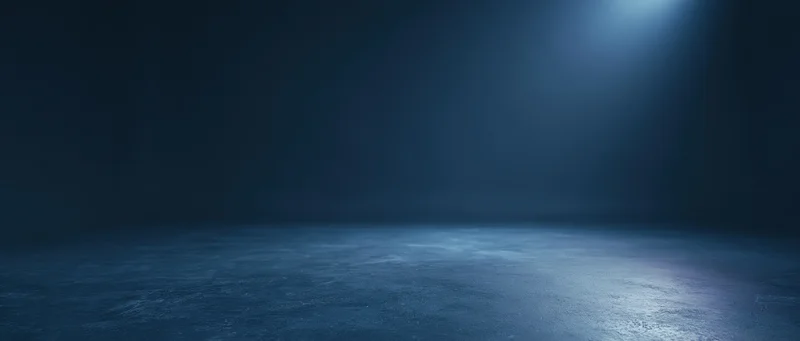 Spotlight illuminating an empty concrete floor in a dark studio space