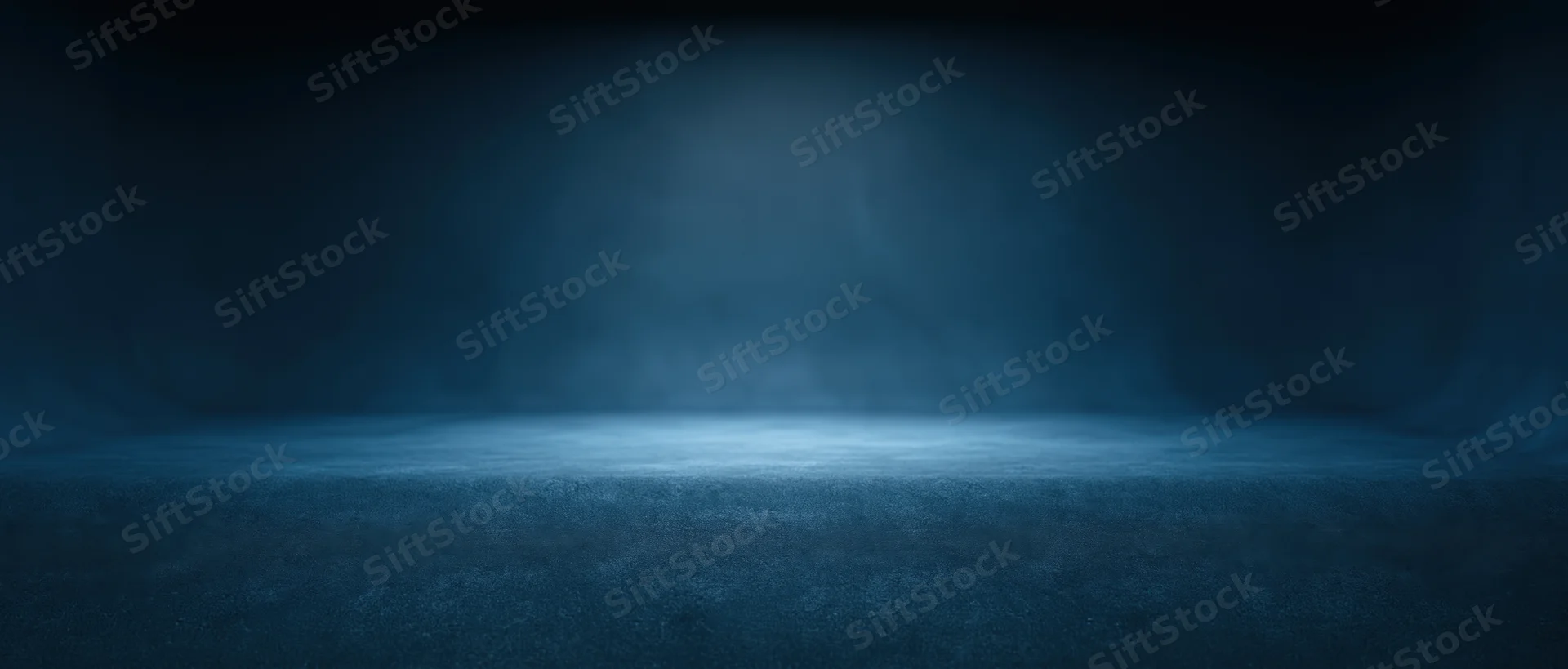 Empty studio space with spotlight and haze on dark blue floor