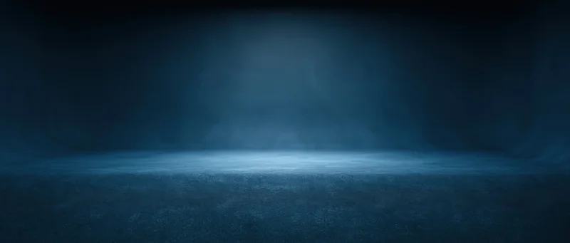 Empty studio space with spotlight and haze on dark blue floor
