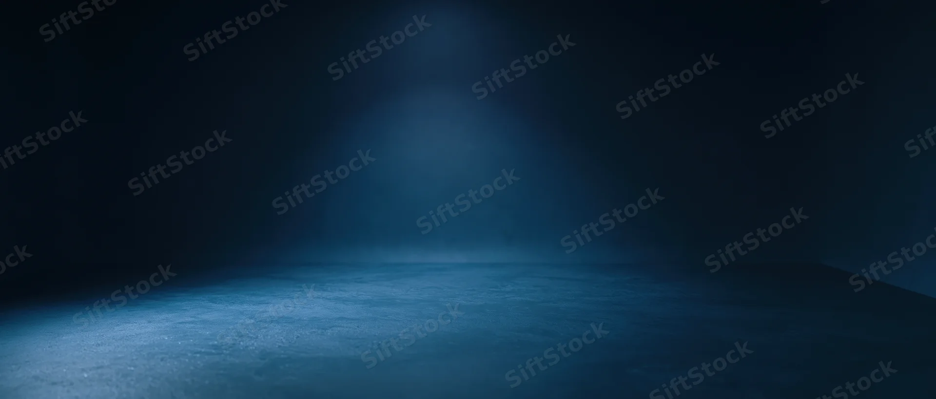 Spotlight illuminating an empty concrete floor in a dark room