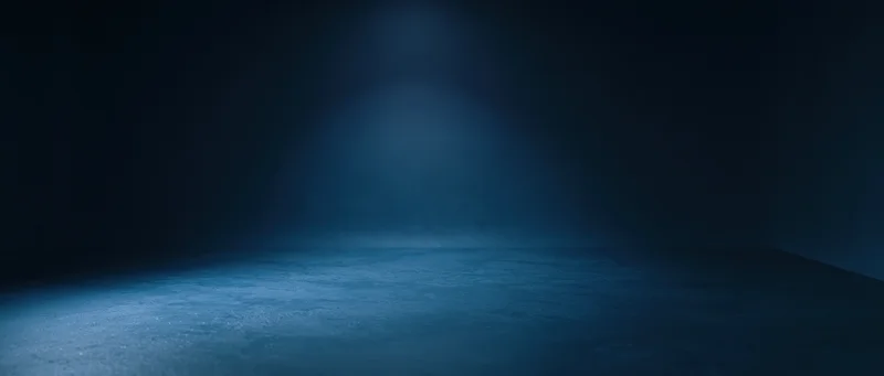 Spotlight illuminating an empty concrete floor in a dark room