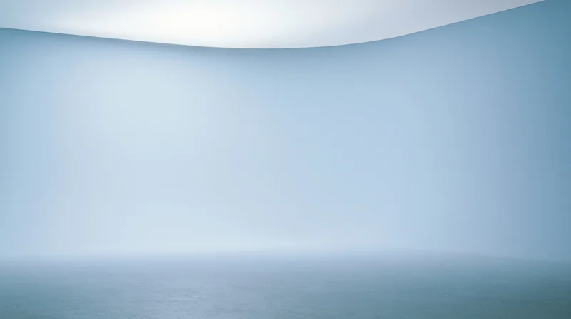 A curved blue gradient surface with soft light and foggy horizon over calm water