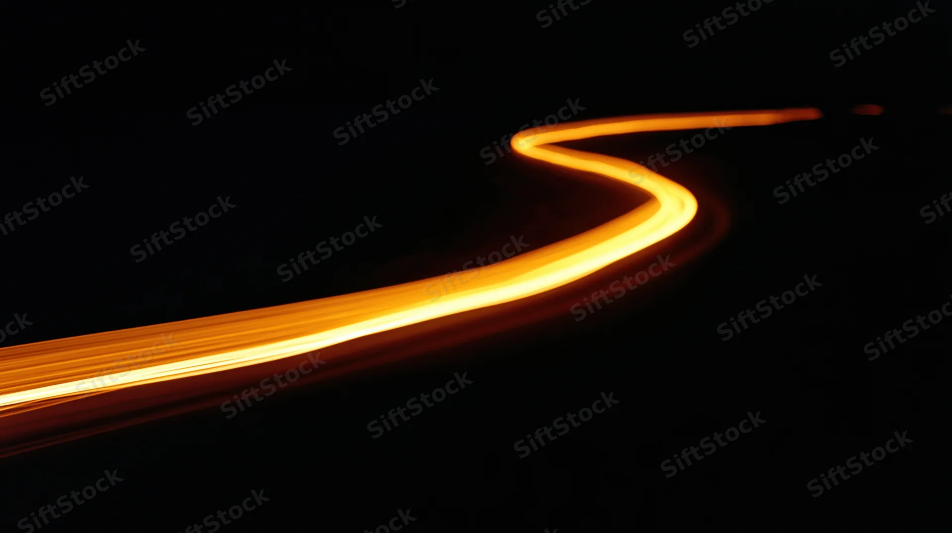 Glowing light trail curving through darkness at night