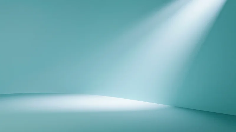 A spotlight beam illuminating a corner of a teal studio room with soft glow on floor and wall