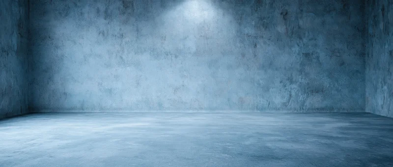 Empty concrete room with spotlight on textured wall and floor, interior space for display or photography