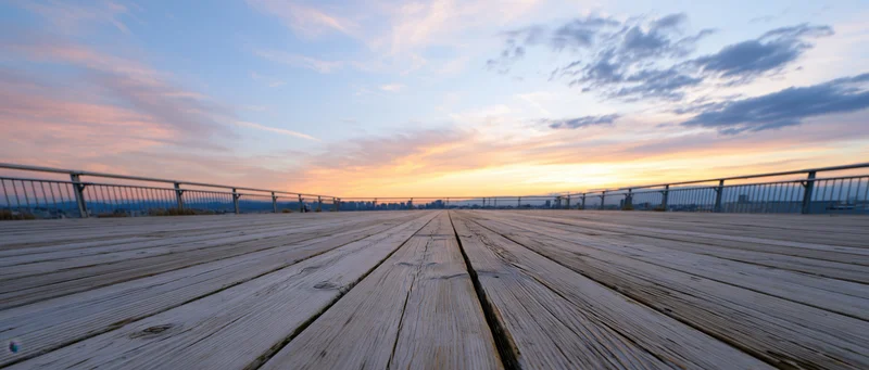 Wooden deck extending toward city skyline at sunset over waterfront