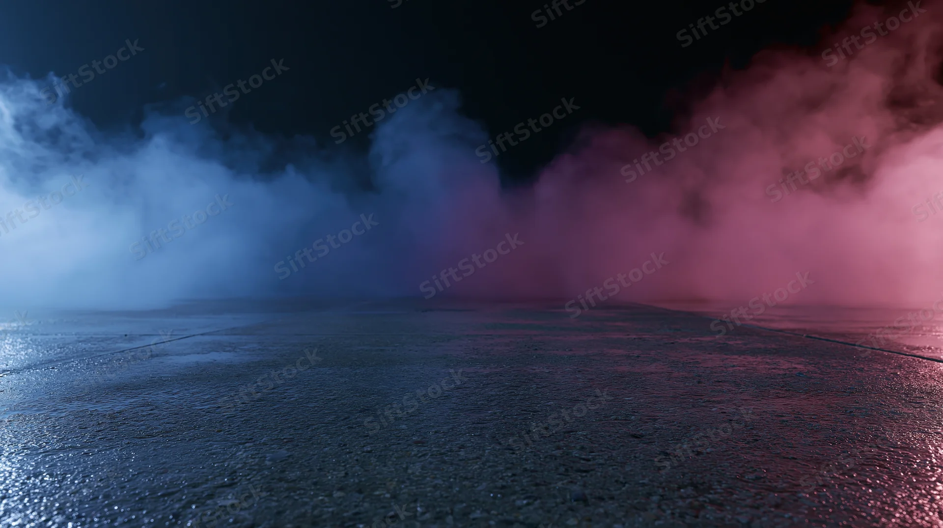 Colored smoke drifting over wet pavement at night