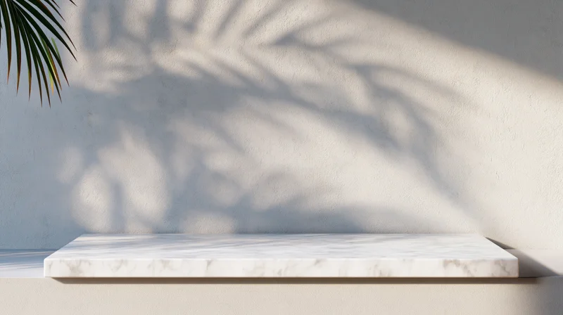 White marble shelf against textured wall with palm leaf shadow in bright sunlight