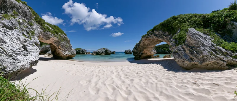 White sandy beach framed by natural rock arches overlooking turquoise ocean under blue sky