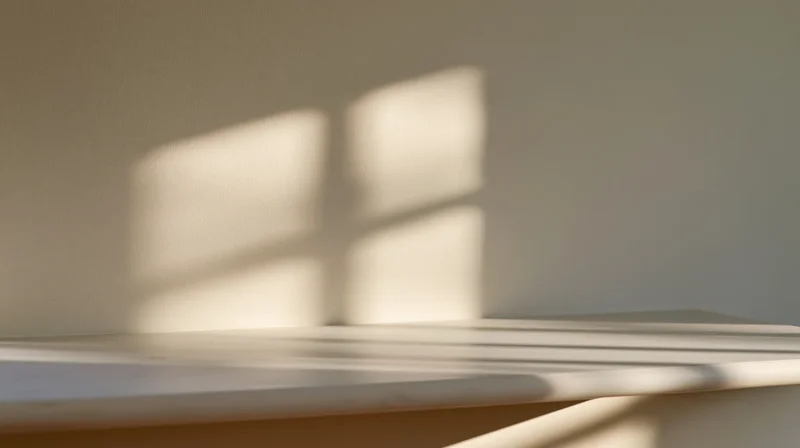 Sunlight casting window shadow on white table and wall in minimalist interior