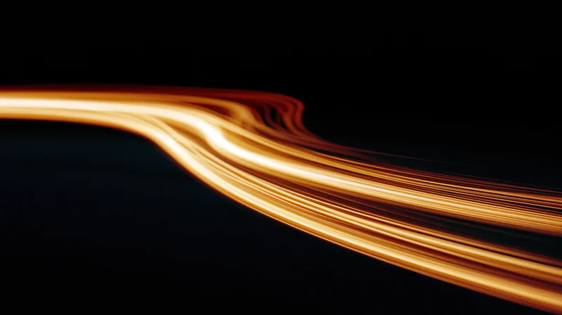 Glowing light streaks curving across a dark background in long exposure motion blur