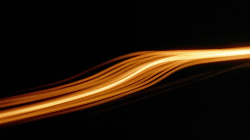 Glowing orange light streaks curving across a dark background in long exposure motion blur