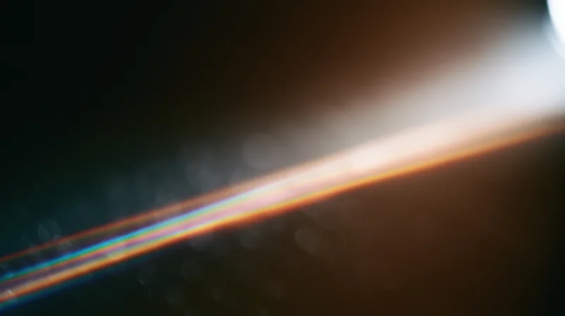 Bright light flare with rainbow spectrum across dark background, creating soft bokeh and lens flare effect