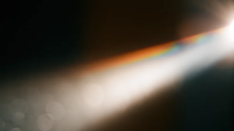 Bright light with rainbow lens flare and soft bokeh effect across a dark background