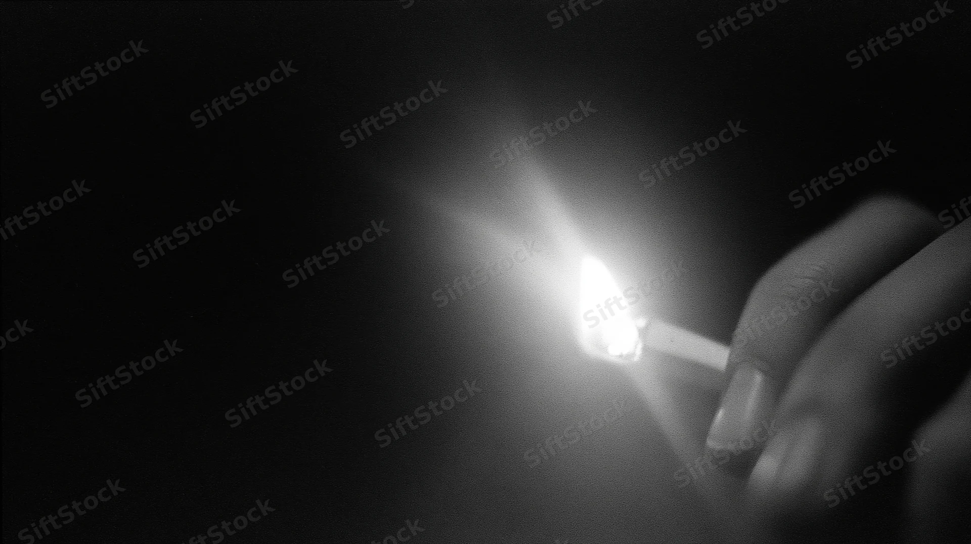 Hand holding lit match in dark space