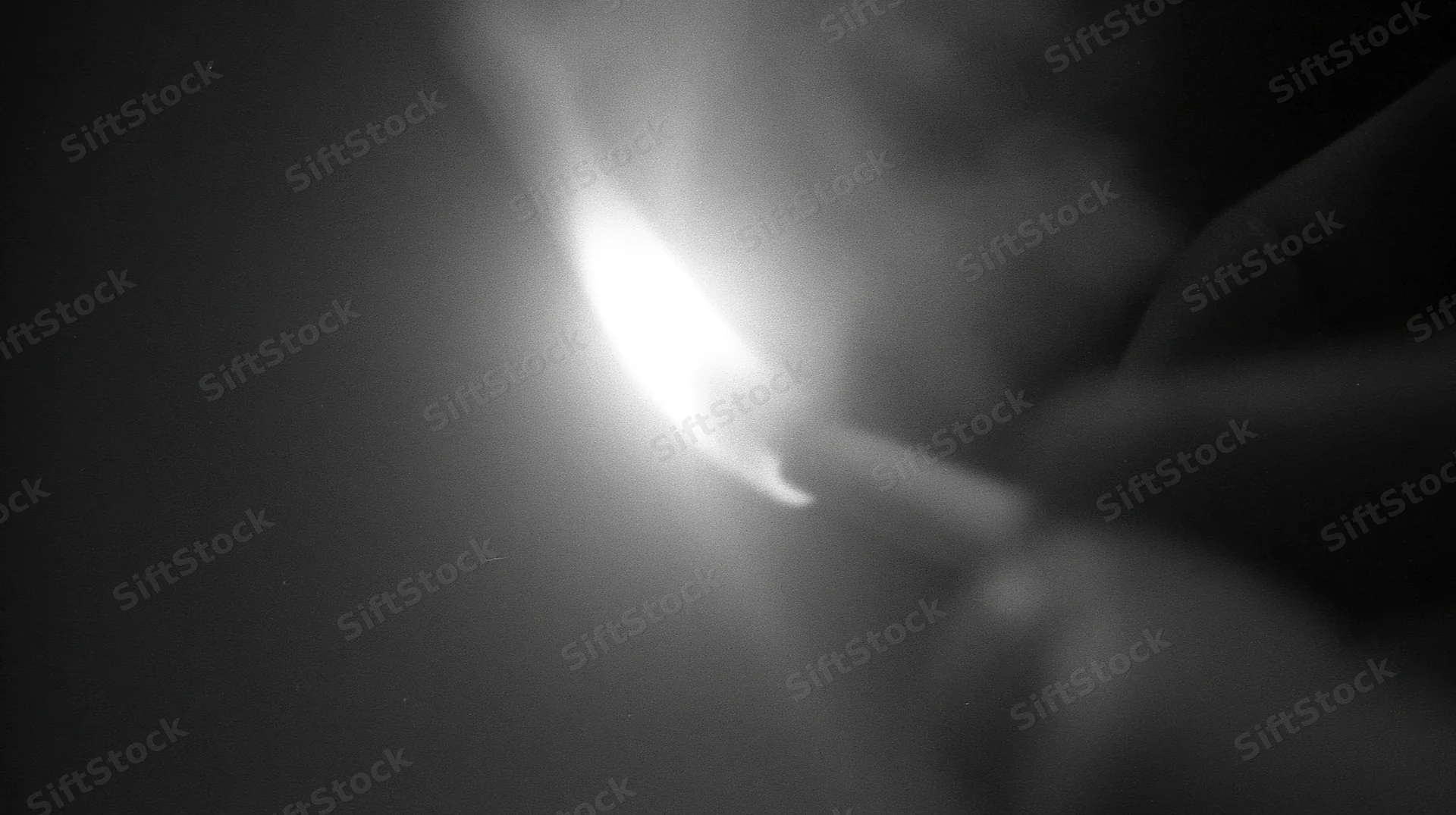 Hand lighting a cigarette in dark, smoke rising, close-up view