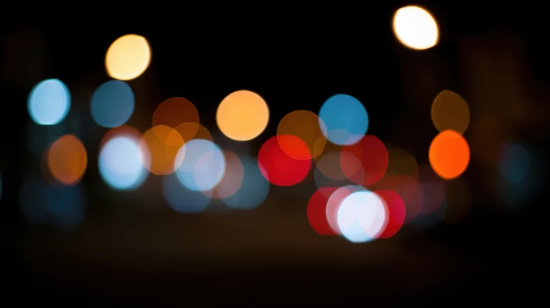 Blurred circular lights from city traffic at night creating a bokeh effect in the urban background