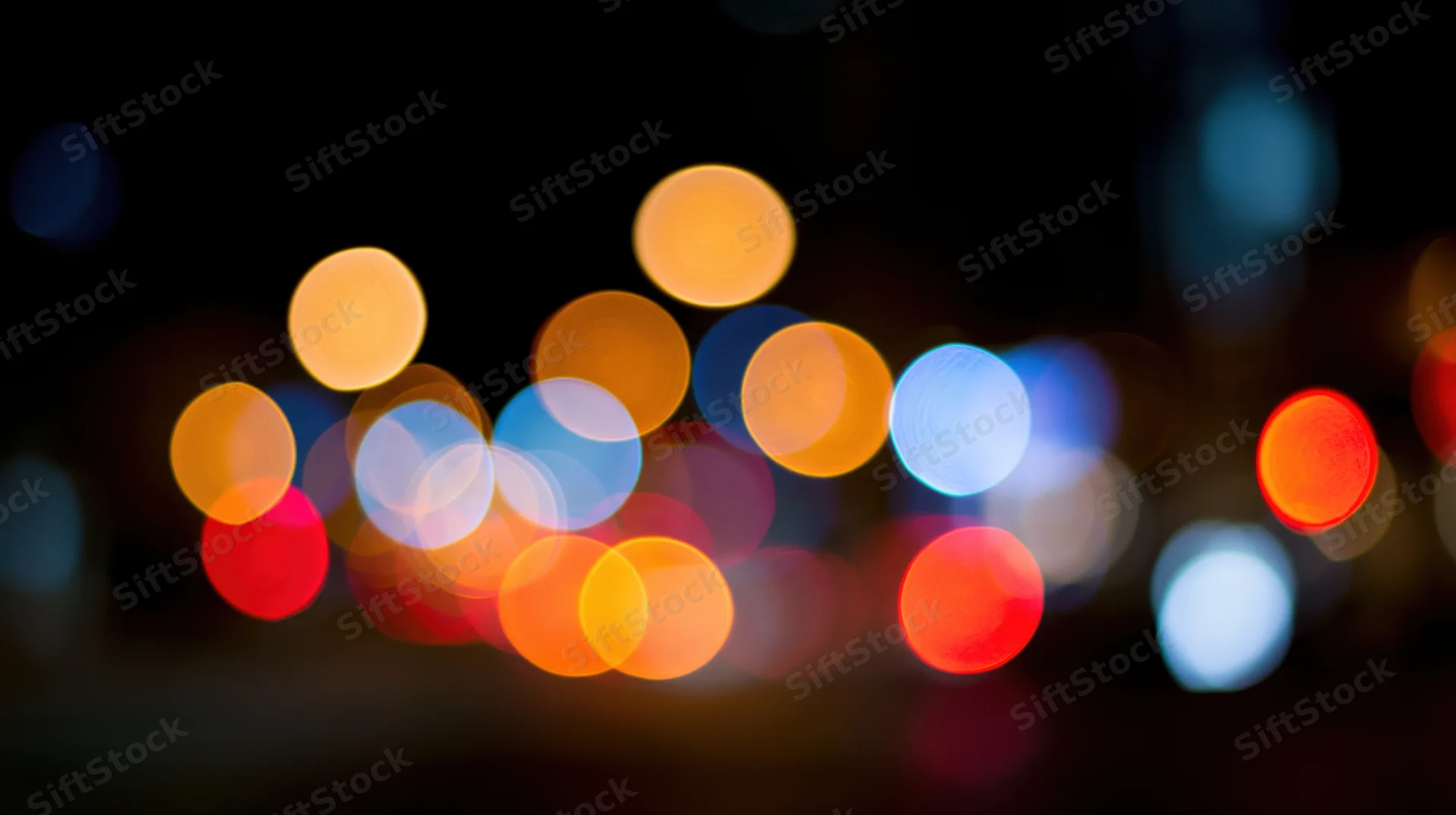Blurred circular lights from city traffic at night forming a bokeh effect in the urban background