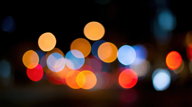 Blurred circular lights from city traffic at night forming a bokeh effect in the urban background